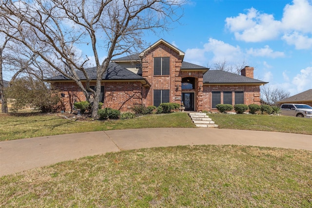 view of front of property with a front lawn, brick siding, and a chimney