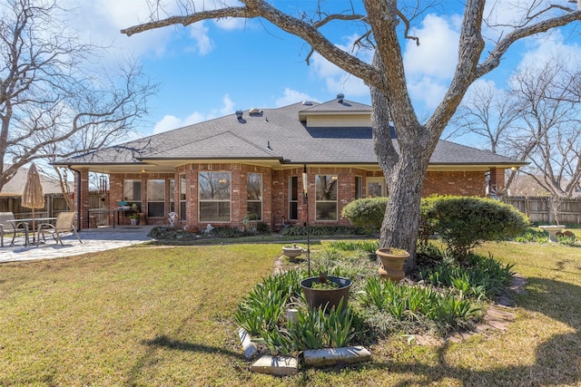 back of house with a patio, fence, a shingled roof, a lawn, and brick siding