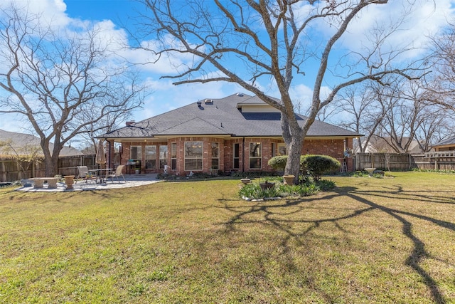 rear view of property with a yard, brick siding, a fenced backyard, and a patio area