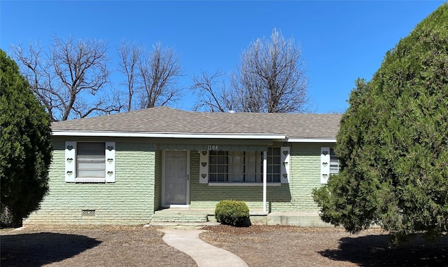 view of front facade with a shingled roof, brick siding, and crawl space