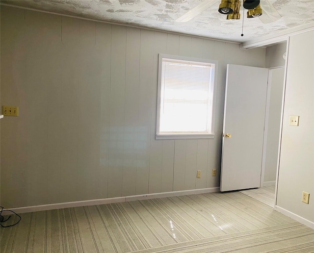 spare room featuring baseboards, light wood-type flooring, and a ceiling fan