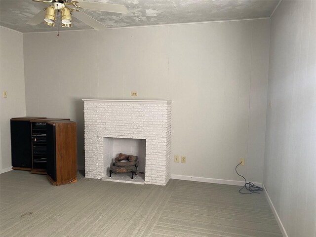 unfurnished living room with a brick fireplace, a ceiling fan, and baseboards