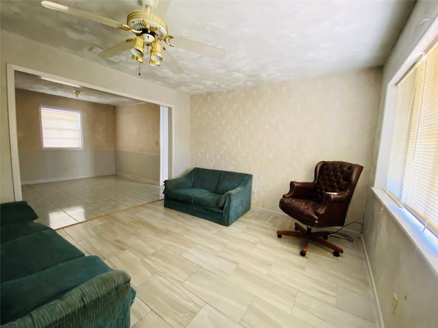 living room with baseboards and ceiling fan