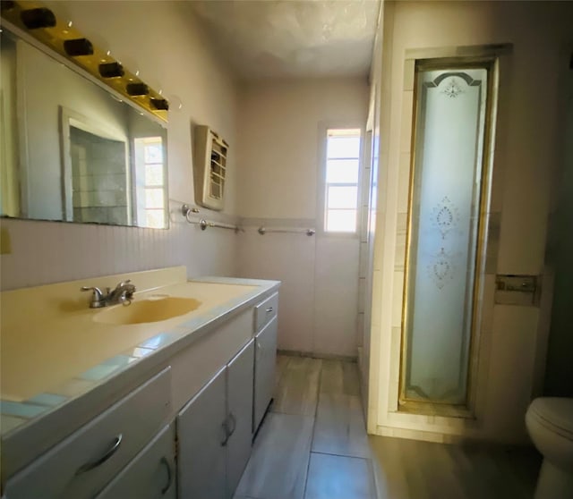 full bathroom featuring a wainscoted wall, vanity, a shower stall, and toilet