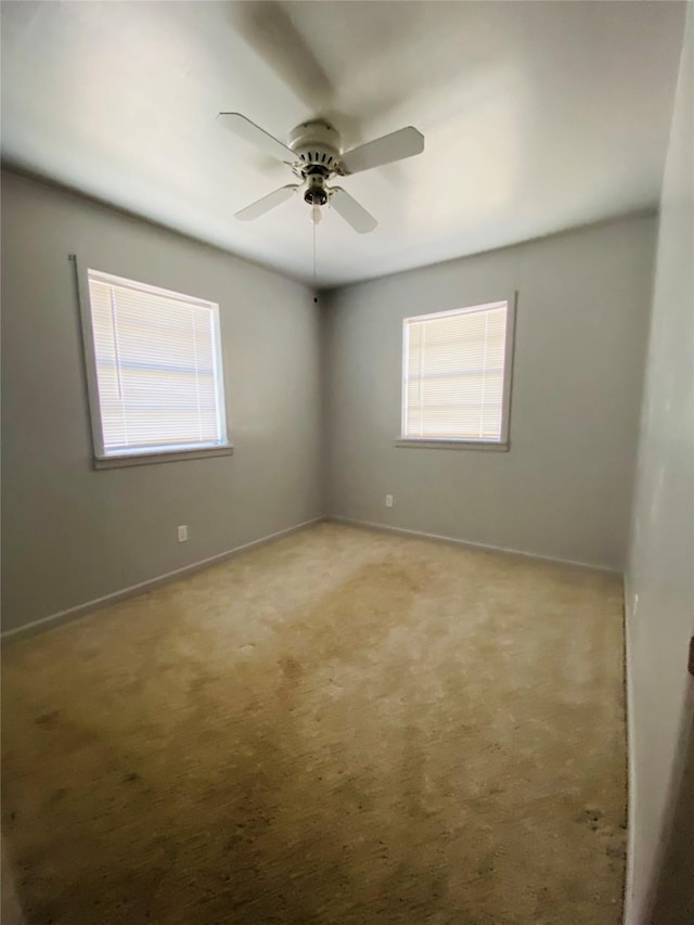 unfurnished room with a ceiling fan, carpet, baseboards, and a wealth of natural light