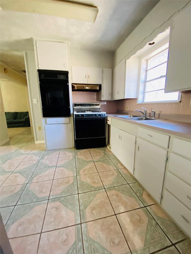 kitchen with oven, under cabinet range hood, light tile patterned floors, range with gas stovetop, and a sink