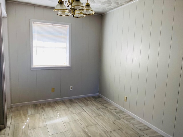 unfurnished room featuring baseboards and an inviting chandelier