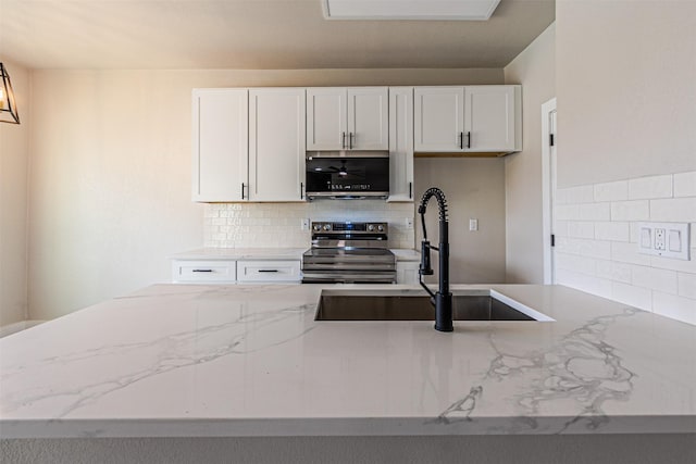 kitchen with white cabinets, light stone countertops, appliances with stainless steel finishes, and a sink