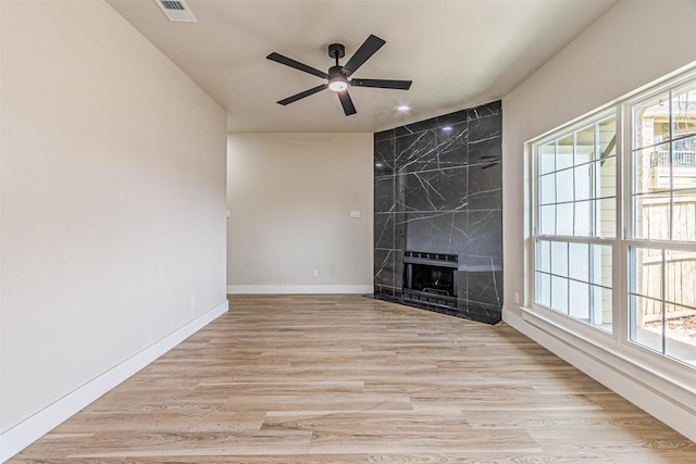 unfurnished living room featuring wood finished floors, visible vents, baseboards, a fireplace, and ceiling fan