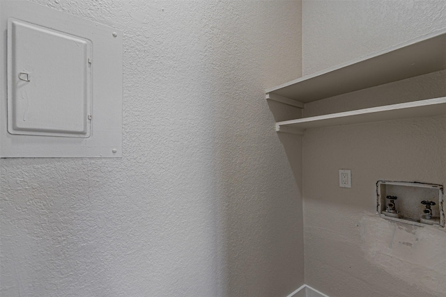 clothes washing area with electric panel, washer hookup, laundry area, and a textured wall