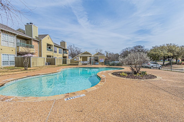 community pool with a gazebo, a patio, and fence