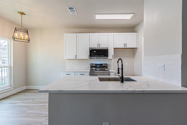 kitchen featuring visible vents, a sink, light stone counters, stainless steel appliances, and white cabinets