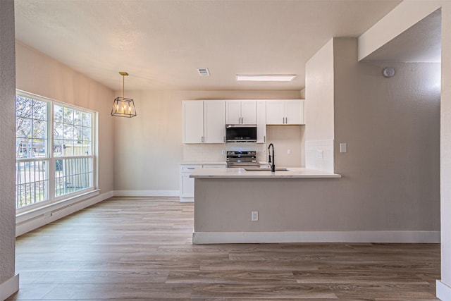 kitchen featuring decorative backsplash, light wood-style floors, white cabinets, stainless steel appliances, and a sink