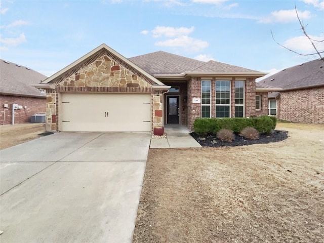 view of front of house featuring central air condition unit, stone siding, concrete driveway, an attached garage, and brick siding