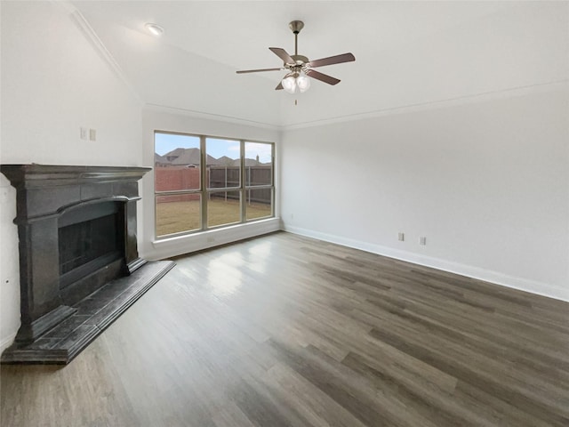 unfurnished living room featuring wood finished floors, baseboards, a fireplace with raised hearth, ceiling fan, and ornamental molding