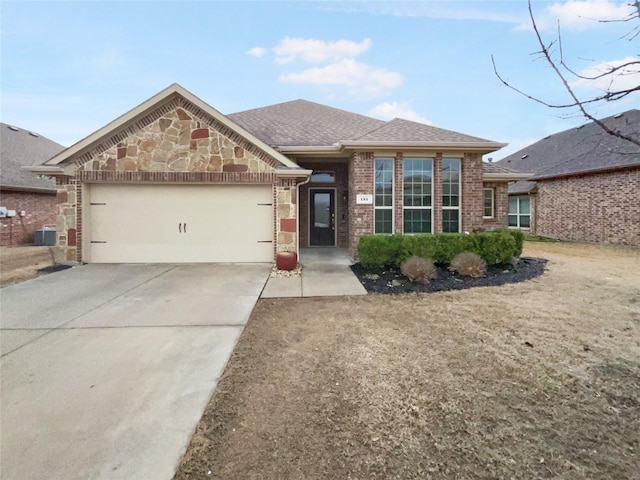 view of front of house featuring driveway, stone siding, roof with shingles, an attached garage, and brick siding