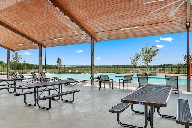 view of patio with a community pool and fence