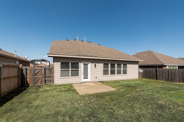 back of house featuring a patio area, a lawn, a fenced backyard, and a gate