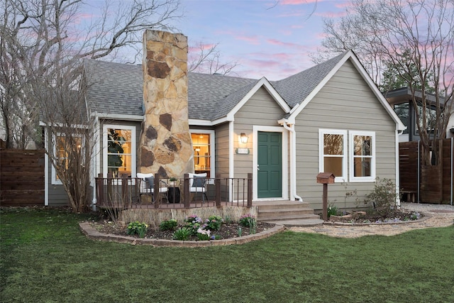 view of front of house featuring a yard, fence, and roof with shingles