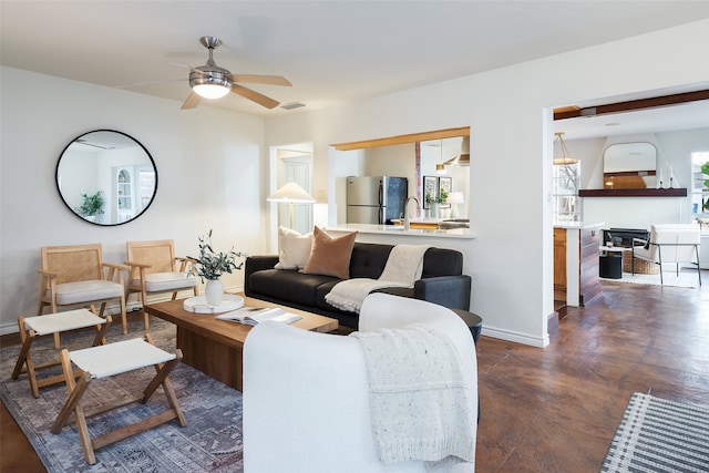 living area featuring visible vents, a ceiling fan, and baseboards