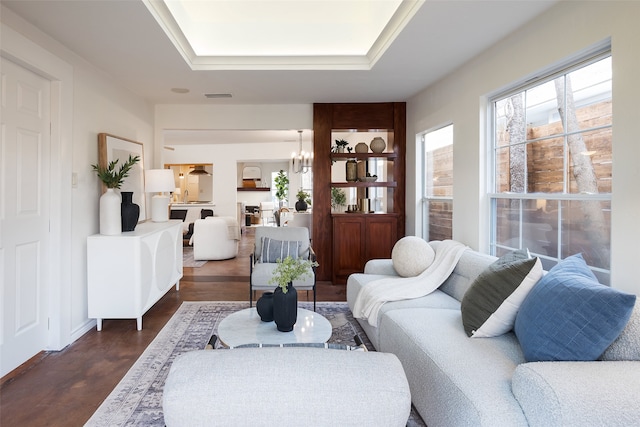 living area with a tray ceiling, a chandelier, dark wood-style flooring, and visible vents