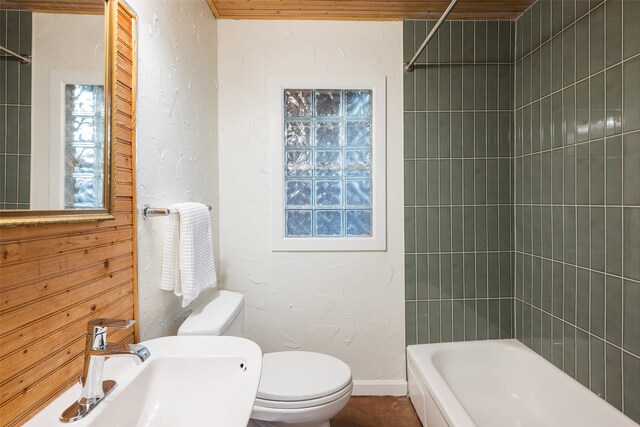 full bath with toilet, a sink, baseboards, bathing tub / shower combination, and a textured wall