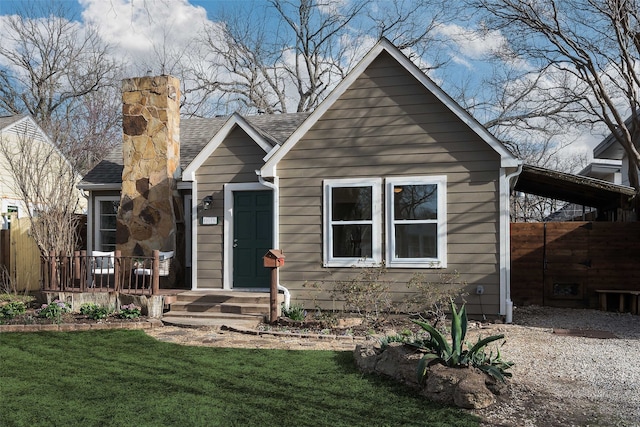 view of front of property with a carport, a chimney, a front yard, and a shingled roof