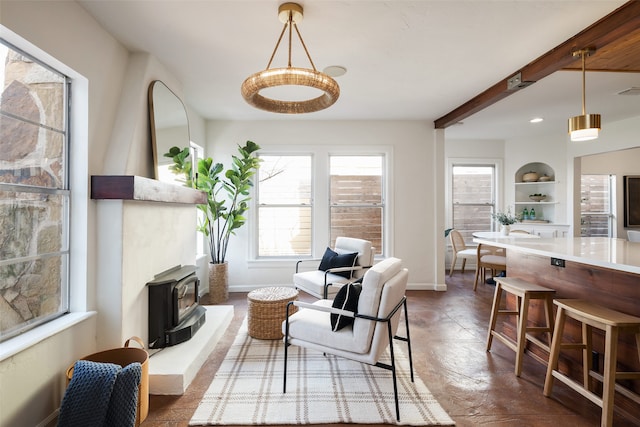 sitting room featuring a wood stove, recessed lighting, beamed ceiling, and baseboards