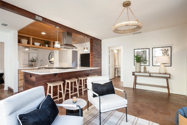 kitchen featuring wall chimney range hood, light countertops, visible vents, stainless steel gas cooktop, and hanging light fixtures