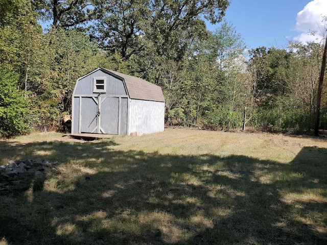 view of yard with a storage shed, an outbuilding, and a wooded view