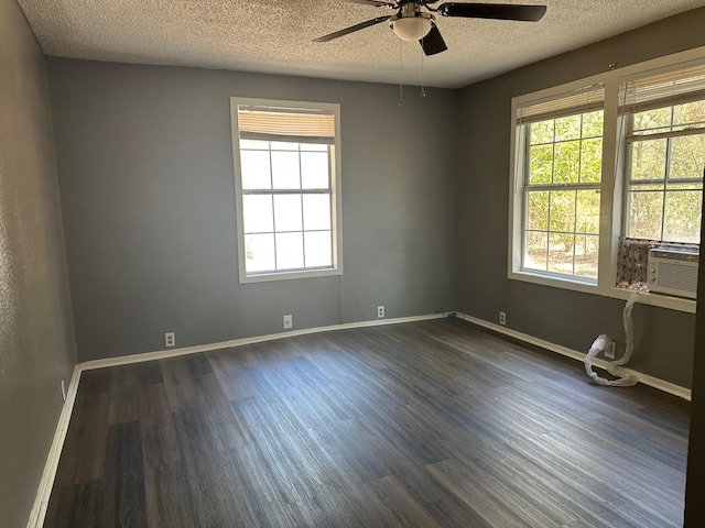 spare room with a ceiling fan, a textured ceiling, dark wood-style floors, cooling unit, and baseboards