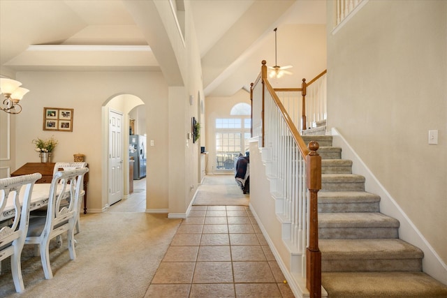 foyer with arched walkways, stairway, light carpet, and a high ceiling