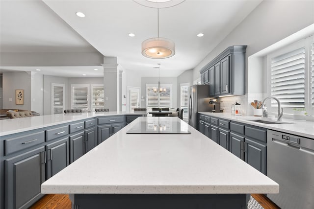 kitchen with a sink, a spacious island, appliances with stainless steel finishes, and gray cabinetry