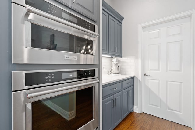 kitchen featuring oven, tasteful backsplash, wood finished floors, and gray cabinets