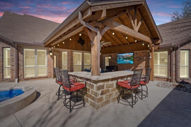 patio terrace at dusk featuring outdoor dry bar and ceiling fan