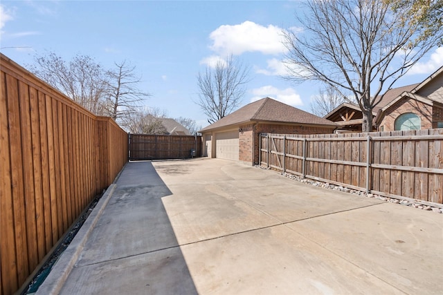 view of patio / terrace featuring concrete driveway, a fenced backyard, and an outdoor structure