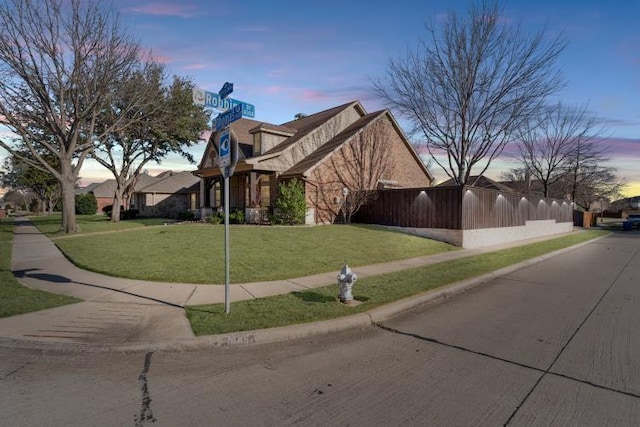 property exterior at dusk with a yard and fence