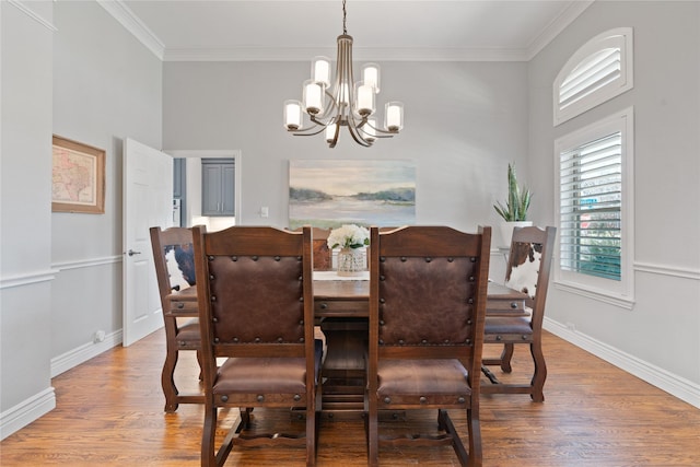 dining space with a chandelier, baseboards, wood finished floors, and crown molding