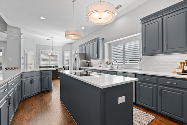 kitchen with a sink, a kitchen island, freestanding refrigerator, black electric stovetop, and dark wood-style flooring