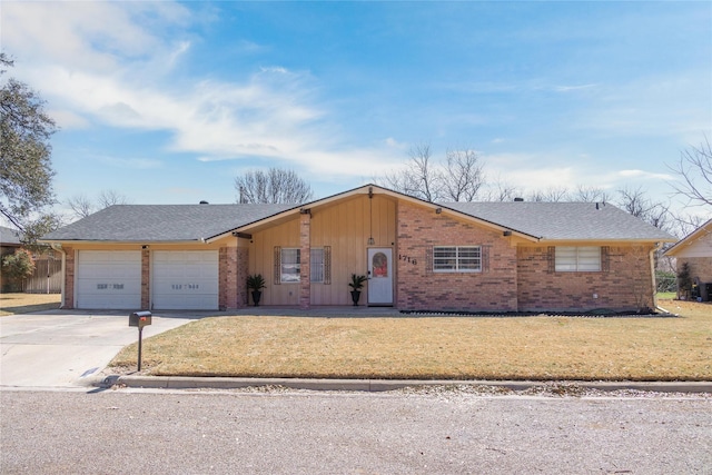 view of front of property featuring a front yard, a shingled roof, concrete driveway, a garage, and brick siding