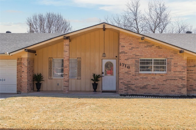 view of front of house with a front lawn, brick siding, roof with shingles, and an attached garage