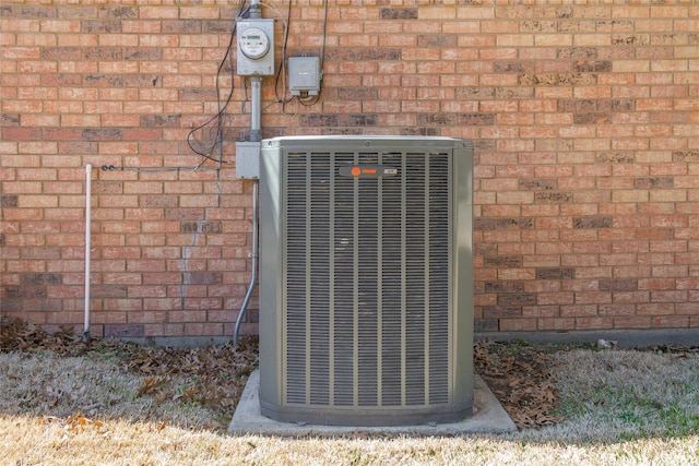 exterior details with cooling unit, brick siding, and electric meter