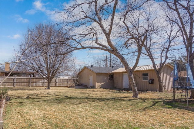 view of yard featuring an outbuilding, a trampoline, and fence