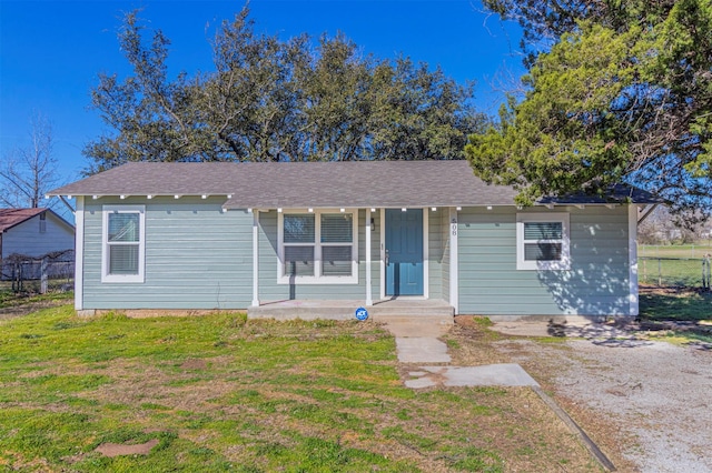 ranch-style house with a shingled roof, a front lawn, and fence