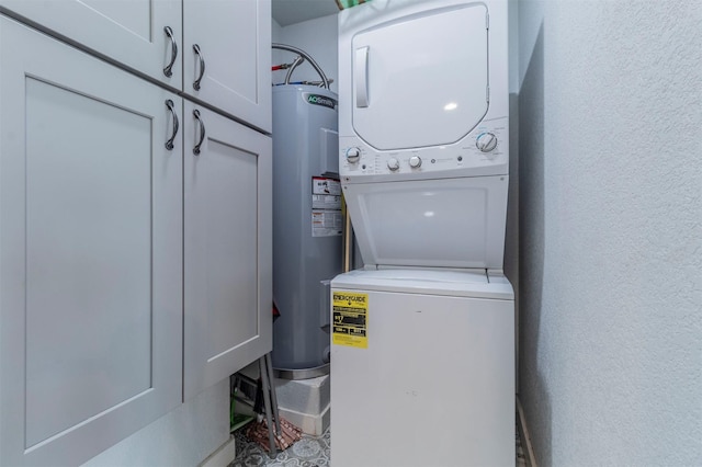 laundry room featuring stacked washer / drying machine, cabinet space, electric water heater, and a textured wall