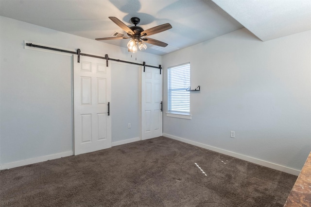 unfurnished bedroom with a barn door, baseboards, carpet floors, and ceiling fan