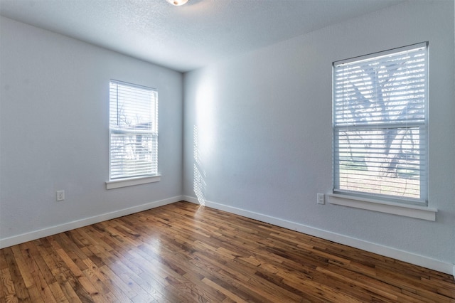 empty room with baseboards, a healthy amount of sunlight, and wood-type flooring