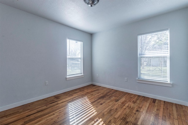 unfurnished room with hardwood / wood-style flooring, baseboards, and a textured ceiling