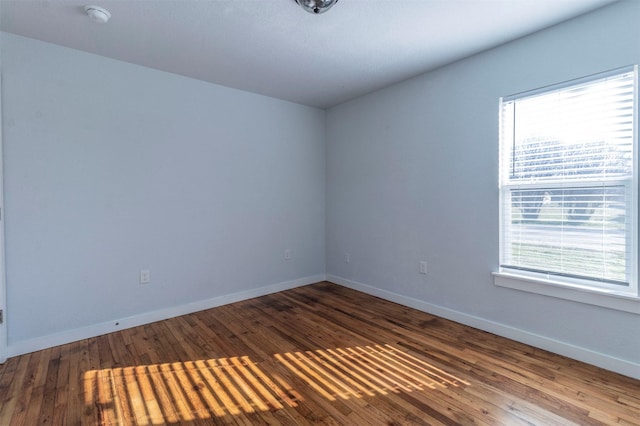 spare room with baseboards and wood finished floors