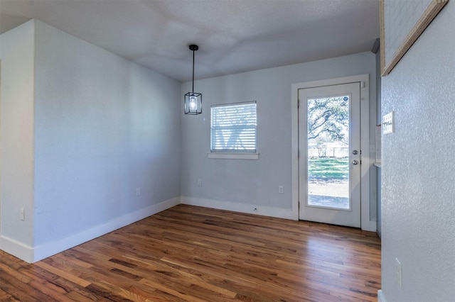 unfurnished dining area featuring dark wood-style floors and baseboards